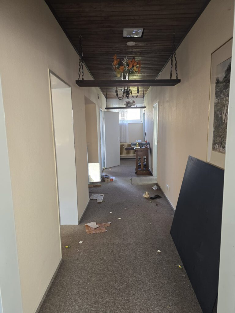 Seitengang – Zustand vor Beginn der Arbeiten → Dekoration, Teppichboden und diverse Möbelteile noch vorhanden.